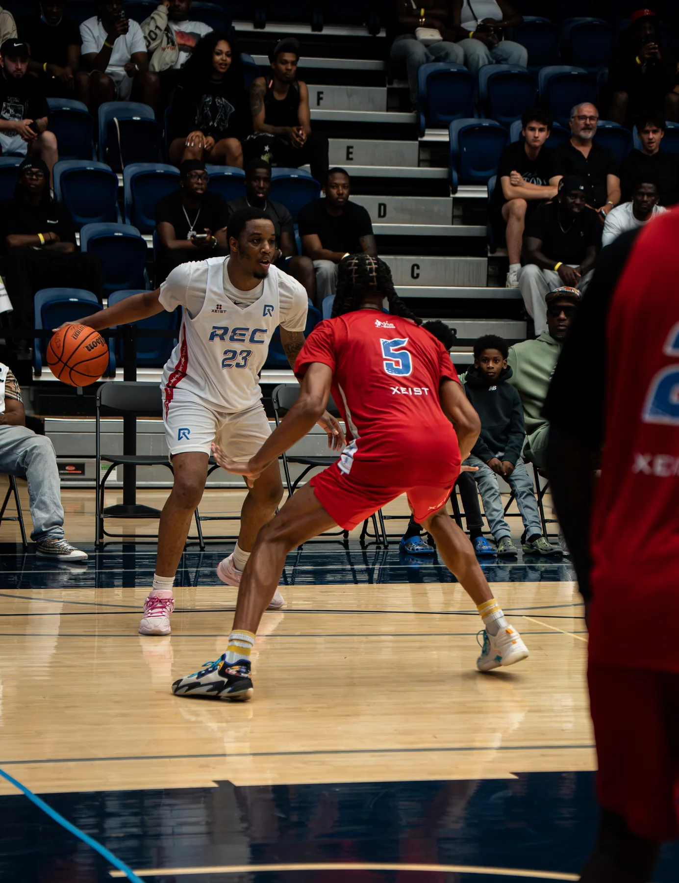 A player in white dribbles toward a defender in red during a Mania Weekend game.
