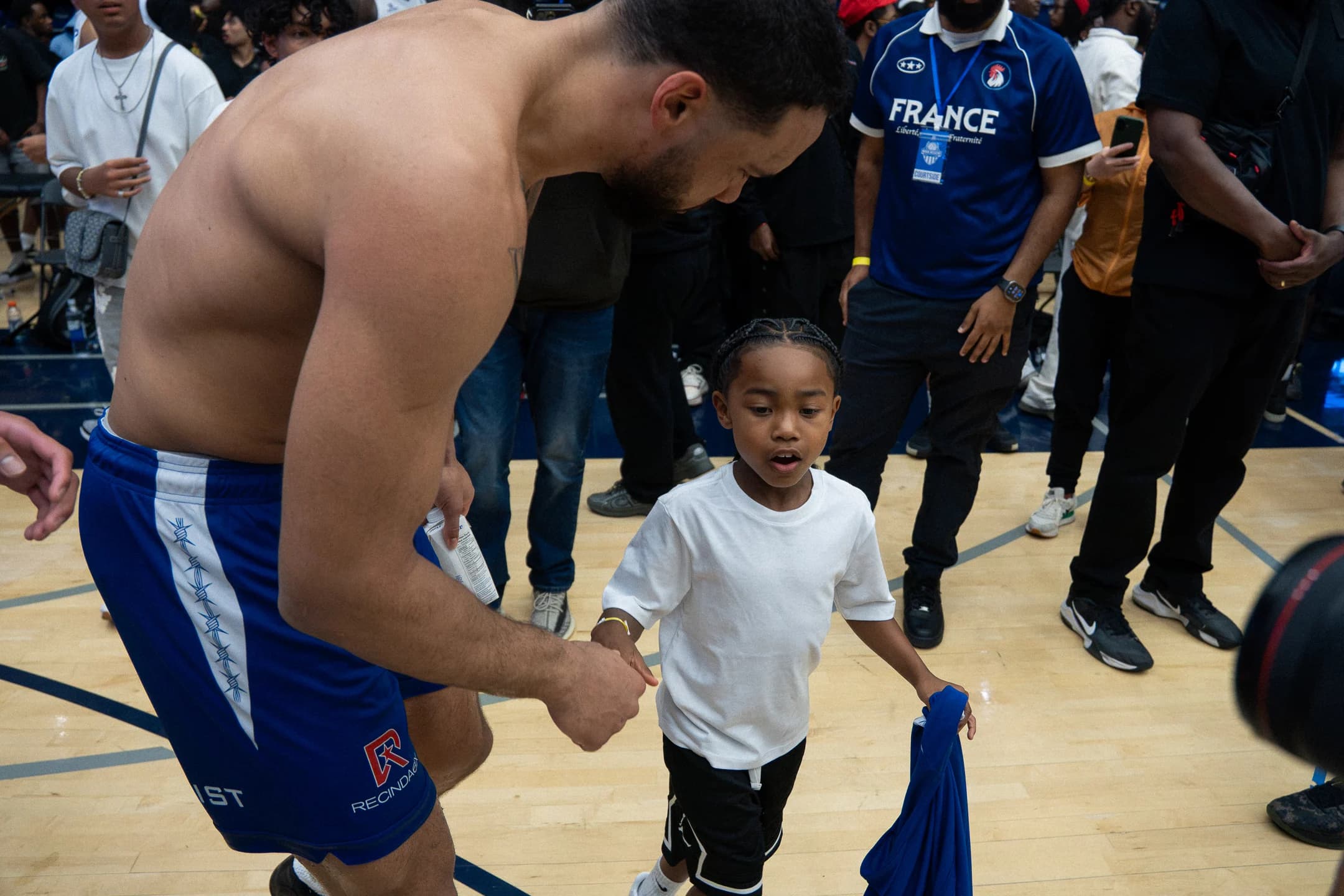 A basketball player leans down to greet a young fan on the court at Mania Weekend 2026.