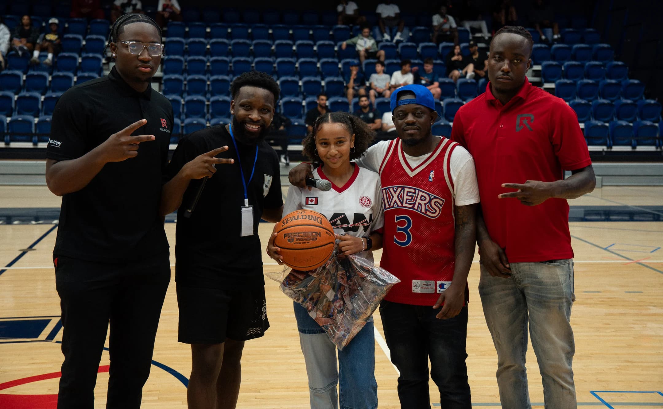 A young attendee holds a basketball while posing with community members at Mania Weekend 2026.